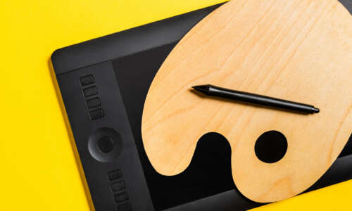 Top View of Wooden Palette And Graphics Tablet With Stylus on Yellow Surface